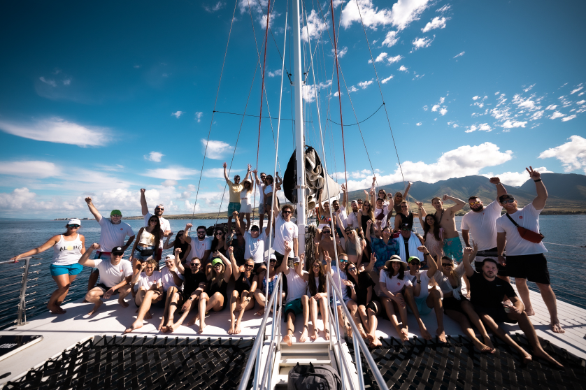 A large group of people on a sailboat cheering with excitment
