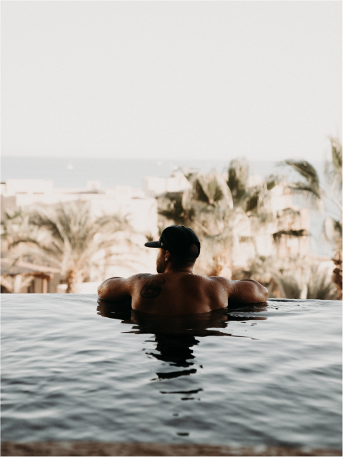 The backside of a man relaxing in a pool in a tropical paradise