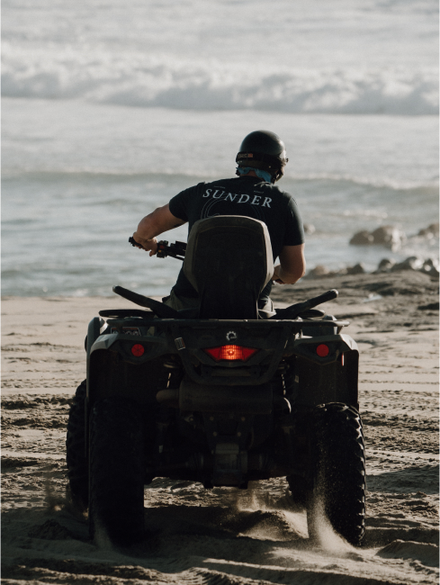 A man driving a four wheeler on a beach