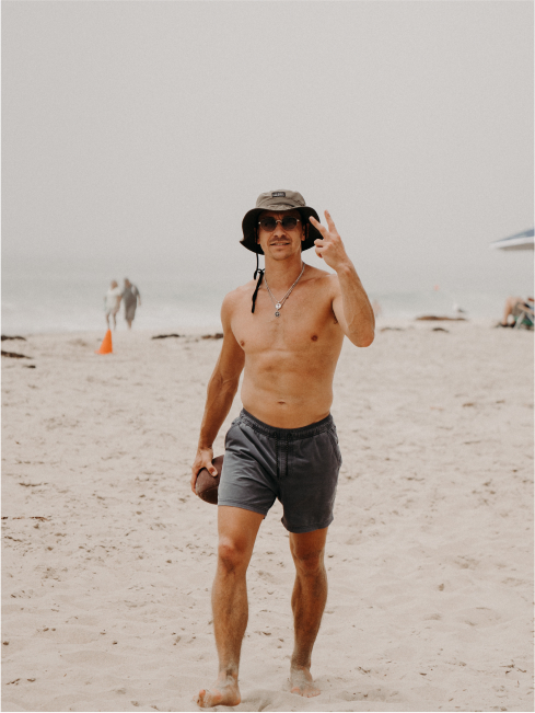 A man on the beach with a bucket hat