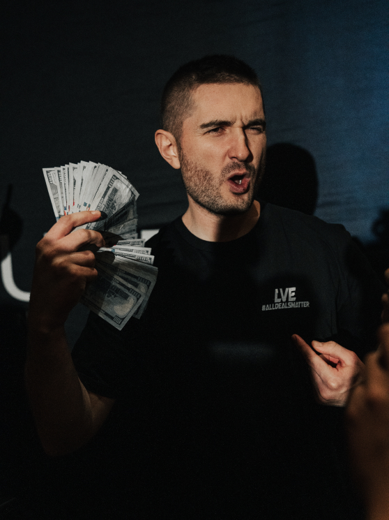A man fanning a bundle of cash, pointing to himself